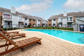 Austin apartment for rent - a swimming pool with two wooden benches next to an apartment building at Northchase, Austin, TX
