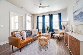 San Antonio apartment for rent - a living room with a brown couch and blue curtains at The Landings at Brooks City-Base, San Antonio, 78235