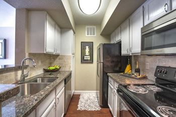 Galley kitchen with white cabinets and granite countertops