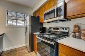 Garland apartment for rent - Kitchen with stainless steel appliances and wood cabinets at The Courtyard Apartments, Texas, 75044