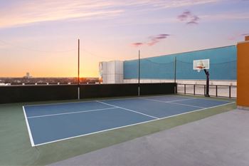 Rooftop sports court with basketball hoop at sunset