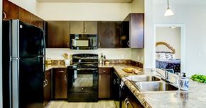 San Antonio apartment for rent - a kitchen with dark wood cabinets and stainless steel appliances at Villa Espada Apartments, San Antonio, TX