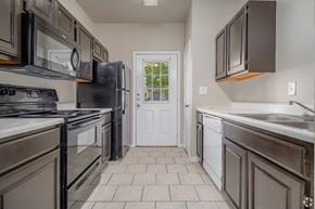 San Antonio apartment for rent - Galley kitchen with white appliances and tile flooring at Houston Street Townhomes Apartments, San Antonio, TX 78220