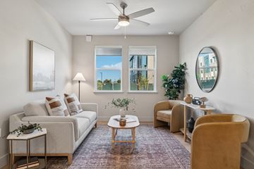 Roseville apartment for rent - A living room with a white couch, a coffee table, a chair, and a painting on the wall.