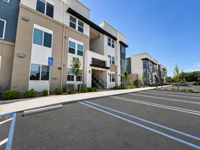 Roseville apartment for rent - A parking lot in front of apartment buildings with a blue sign on the left.