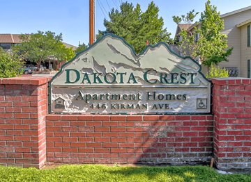 Reno apartment for rent - A sign for Dakota Crest Apartment Homes stands in front of a brick wall.