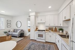 Rocklin apartment for rent - a white kitchen with white cabinets and a living room with a couch