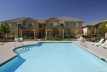 Sacramento apartment for rent - A swimming pool in front of a row of houses.
