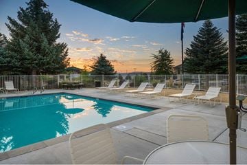 Reno apartment for rent - A pool surrounded by chairs and trees with a sunset in the background.