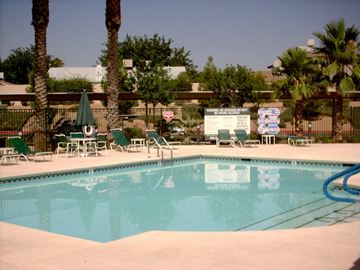 Las Vegas apartment for rent - A pool with a sign in the background and palm trees.