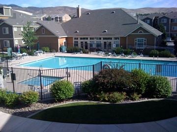 Reno apartment for rent - A swimming pool surrounded by a black fence and bushes.