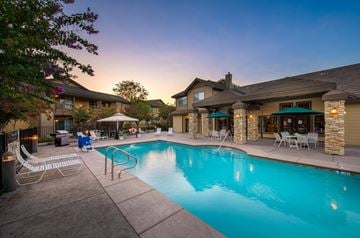 Fair Oaks apartment for rent - A swimming pool surrounded by a patio with chairs and a building in the background.