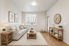 Orange apartment for rent - A living room with a couch, coffee table, and a clock on the wall at The Orion Senior Apartments - Orange, CA Apartments, Orange, California