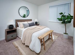 Folsom apartment for rent - a bedroom with a white bedspread and a round mirror on the wall