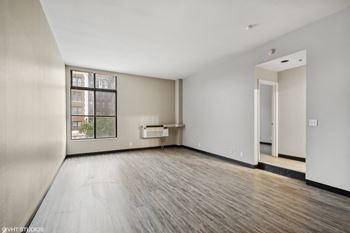 An empty living room with wood floors and a large window