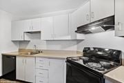 St. Louis apartment for rent - a kitchen with white cabinets and black appliances and a sink at Delmar Loop Apartments, Missouri
