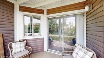 A porch with two chairs and a sliding glass door