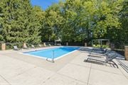 Dublin apartment for rent - A pool surrounded by trees and lounge chairs at Karric Place of Dublin Apartments, Dublin, OH