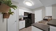 Memphis townhouse for rent - A kitchen with a black refrigerator and white cabinets. at The Local Apartments, Memphis, TN