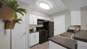 Memphis townhouse for rent - A kitchen with a black refrigerator and white cabinets. at The Local Apartments, Memphis, TN