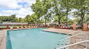 Memphis apartment for rent - A large outdoor swimming pool surrounded by trees and lounge chairs.