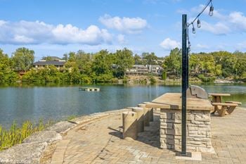A picnic table on a stone patio overlooking a lake