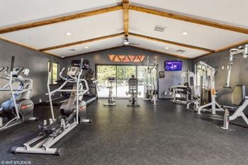 A gym with a variety of equipment including treadmills, weights, and exercise machines.
