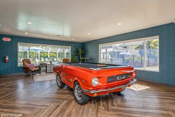 A pool table in a living room with a red car
