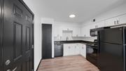 Memphis apartment for rent - A modern kitchen with black cabinets and white appliances. at The District Apartments, Tennessee, 38115