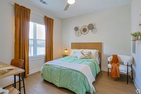 Seguin apartment for rent - A bedroom with a bed, chair, and window at The Virginia Apartments , Seguin, TX