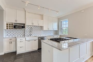 Denver apartment for rent - A kitchen with white cabinets and a black and white tiled backsplash.