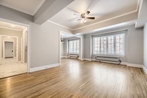 Denver apartment for rent - A spacious room with wooden floors and a ceiling fan.
