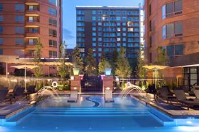 Denver apartment for rent - A large outdoor swimming pool surrounded by lounge chairs and lit by lights.