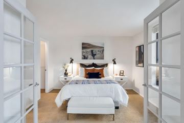 Denver apartment for rent - A white bedroom with a large bed and a fireplace.