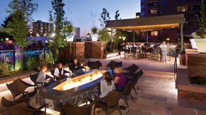 Denver apartment for rent - A group of people are sitting around a fire pit on a rooftop patio.