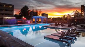 Denver apartment for rent - A pool with lounge chairs and a sunset in the background.
