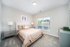 Westerville apartment for rent - A bedroom with a large bed and a window with blinds.