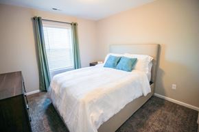 Canal Winchester apartment for rent - a bedroom with white bedding and green pillows