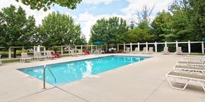 Reynoldsburg townhouse for rent - A large swimming pool surrounded by lounge chairs and trees.