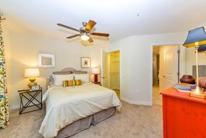 Roswell apartment for rent - A bedroom with a bed, a ceiling fan, and a nightstand with a lamp.