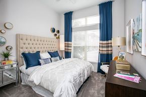 Atlanta apartment for rent - A bedroom with a large bed and a nightstand with a lamp.