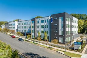 Atlanta apartment for rent - A modern multi-story building with a parking lot in front.