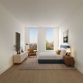 Brooklyn apartment for rent - A bedroom with a large bed, a chair, and a window overlooking a cityscape.