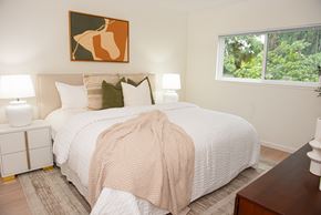 San Jose apartment for rent - A bedroom with a large bed and a painting above it.