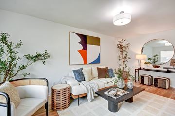 San Jose apartment for rent - A living room with a white couch, a coffee table, and a large abstract painting on the wall.