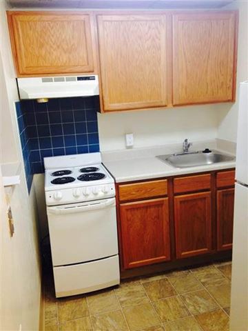 Baltimore apartment for rent - A kitchen with a white stove and wooden cabinets.