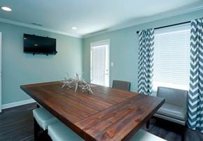 Falls Church apartment for rent - A wooden dining table with chairs and a TV mounted on the wall.