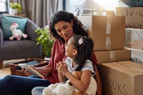 Arlington apartment for rent - A woman and a young girl are surrounded by moving boxes while the woman reads a book to the girl.
