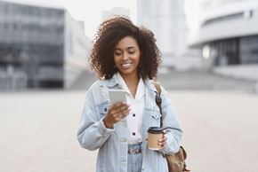 Arlington apartment for rent - A woman with curly hair is holding a cup and looking at her phone.