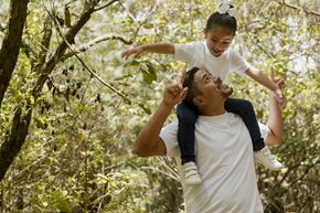 Arlington apartment for rent - A man lifts a child into the air in a forest.